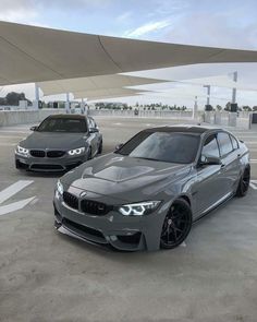 two cars parked in a parking lot next to each other on the cement and concrete floor