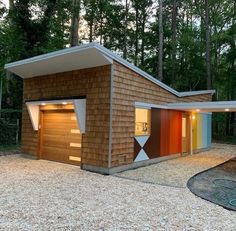 two garages in the middle of a gravel area with trees behind them and lights on