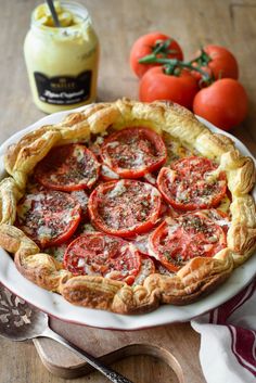 a tomato pie on a plate next to tomatoes and a jar of mayonnaise