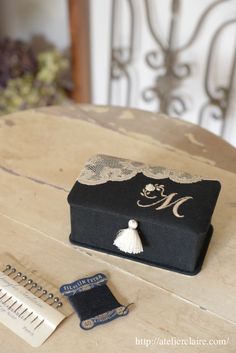 a small black box sitting on top of a wooden table next to a notepad