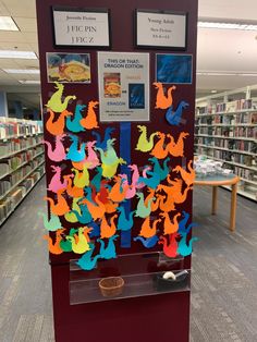 a display in a library filled with lots of colorful paper cutouts on top of bookshelves