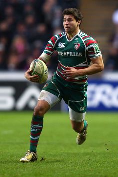 a rugby player is running with the ball in his hand as he prepares to kick it