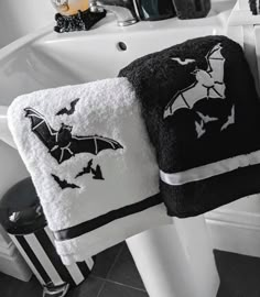 two black and white towels hanging on the side of a sink