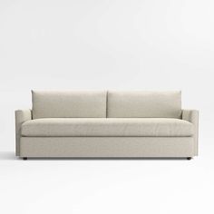 a white couch sitting on top of a white floor next to a wall with a light colored background