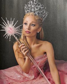 a woman wearing a tiara and holding a pink umbrella in front of her face