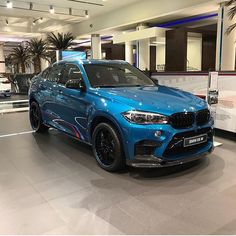 a blue bmw suv is on display in a showroom with palm trees behind it