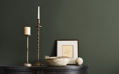 a table with a bowl and two candles on it next to a framed photograph, candle holder and other items