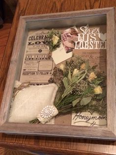 a wooden frame with some flowers and other things in it on top of a table