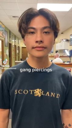 a young man with tattoos on his arms and chest is looking at the camera while wearing a t - shirt that says gang piercings