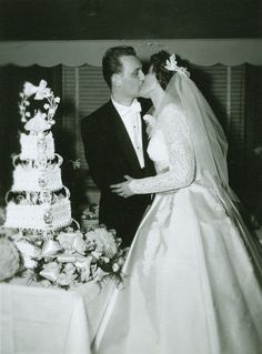 a bride and groom kissing in front of a wedding cake