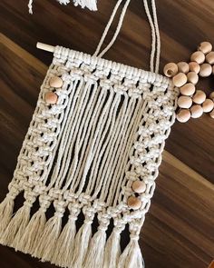 a macrame bag with tassels and beads hanging from it on a wooden table