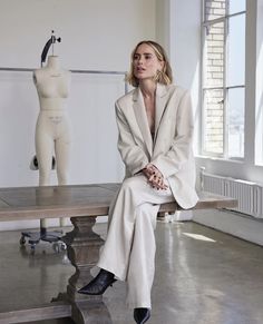 a woman sitting on top of a wooden bench in front of a mannequin