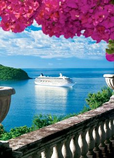 a cruise ship sailing in the ocean near some pink flowers on a balcony with railings