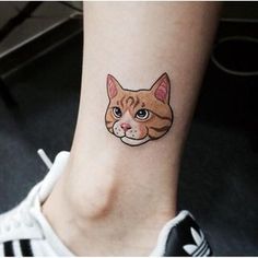 a small tattoo on the ankle of a woman's foot with a cat face