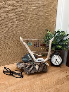 a wooden table topped with a clock and antler head next to a potted plant