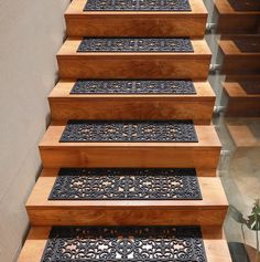 a set of wooden stairs with decorative handrails and floor mats on each step