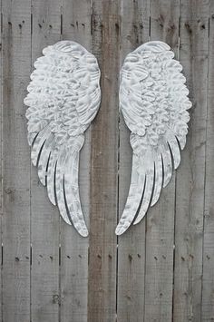 two white angel wings on a wooden fence