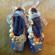 two pairs of shoes with seashells and ribbons on them sitting on the floor