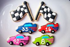 decorated cookies in the shape of race cars are on a white plate with black trim