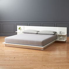 a bed sitting on top of a hard wood floor next to a white headboard