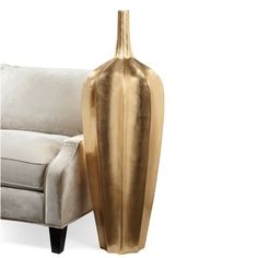 a gold vase sitting next to a white couch