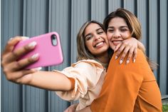 two young women taking a selfie with their cell phone - stock photo - images