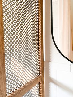 a bathroom with a wooden door and white tile wall next to a mirror on the wall