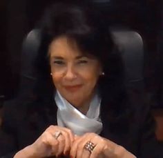 a woman sitting at a desk with her hands on the table and smiling for the camera