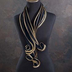 Our UK artisan, Tammy, takes inspiration from tropical forms to create this fashion-forward black and gold sculptural scarf. Handcrafted from silk satin and silk organza, this scarf combines rich gold and black hues for a bold look in a classic colorway. The unique, twisting shape makes this a bold statement piece. Handcrafted for Uno Alla Volta, from the heart and hands of the artisan. Dimensions - Approx. 44'' long. Black Silk Scarf For Party, Luxury Black Silk Scarf For Formal Occasions, Luxury Black Silk Scarf For Evening, Elegant Black Silk Scarf For Party, Elegant Black Silk Party Scarf, Chic Gold Silk Scarves, Chic Gold Silk Scarf, Elegant Black Silk Scarf For Evening, Elegant Gold Scarf For Evening