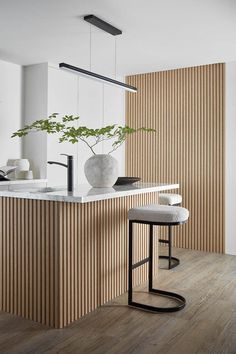 a kitchen with an island and stools in front of the counter top that has a potted plant on it