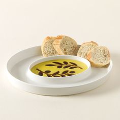 two slices of bread sitting on top of a white plate next to a bowl of oil