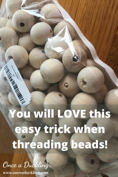 a bag filled with white wooden beads on top of a table next to a sign that reads, you will love this easy trick when thread threading beads