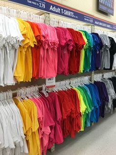 there are many shirts hanging on the rack in this store, all different colors and sizes