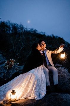 a bride and groom are sitting on rocks with their lantern lights in the foreground