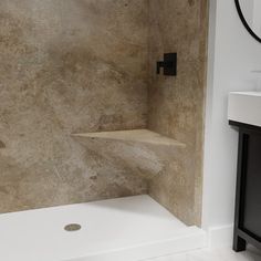 a bath room with a sink and a shower head mounted to the side of a wall