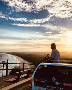 a person sitting on top of a car looking out at the ocean