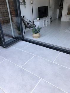 a patio with a chair and potted plant on the floor next to an open sliding glass door