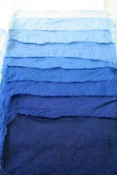 a pile of towels sitting on top of a bed next to each other in different colors