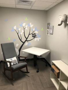 an office with a tree painted on the wall next to a white desk and chair