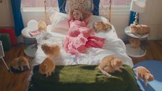 a woman laying in bed surrounded by kittens on the floor next to a window