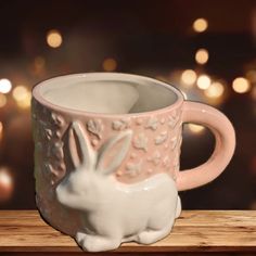 a ceramic mug with a white rabbit on the inside and pink rim, sitting on a wooden table