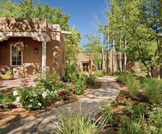 a small house surrounded by lots of trees and flowers in front of the entrance to it