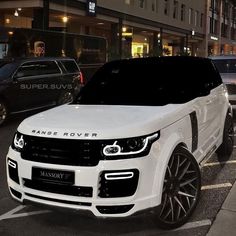 a white range rover parked on the side of a street at night with other cars behind it