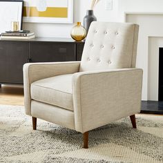 a beige chair sitting on top of a rug in front of a white fire place