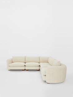 a white sectional couch sitting on top of a wooden table in front of a wall