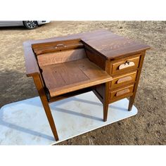 a wooden desk sitting on top of a piece of plywood in the middle of a field