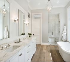 a white bathroom with marble counter tops and double sinks