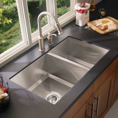 a kitchen sink sitting on top of a counter next to a bowl of fruit and vegetables