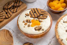 two wooden bowls filled with desserts on top of a white table covered in frosting