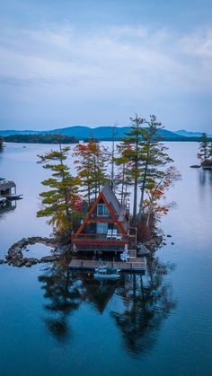 a house on an island in the middle of water with boats and trees around it